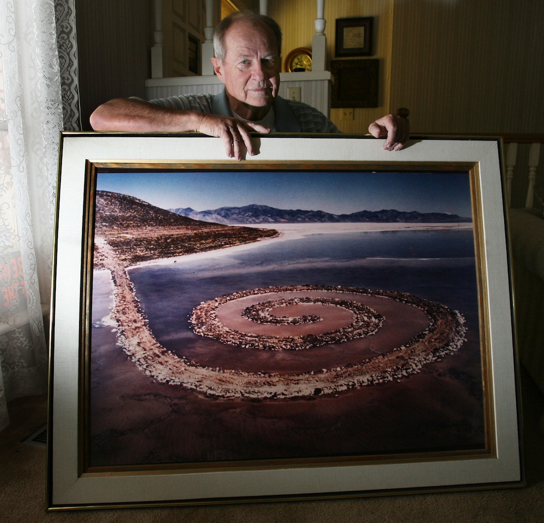 (Steve Griffin  |  Tribune file photo) In this 2011 file photo, Bob Phillips is pictured in his Ogden home holding a giant photograph, taken by photographer Gianfranco Gorgoni of the Spiral Jetty.  Phillips was the contractor who built the Spiral Jetty for artist Robert Smithson.