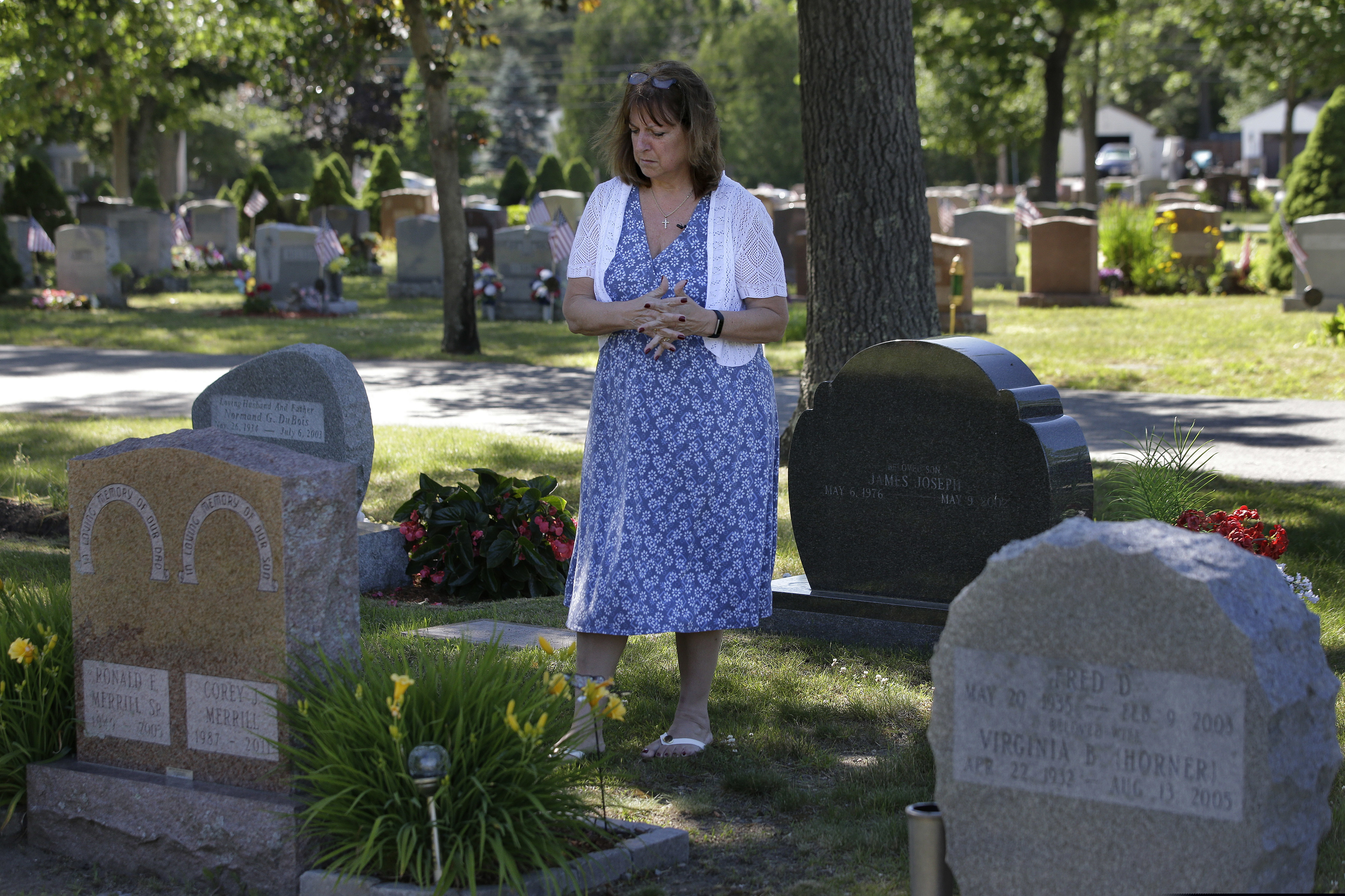 (Steven Senne | AP file photo) Cheryl Juaire, of Marlborough, Mass., stands at her son’s grave, in Chelmsford, Mass., on Tuesday, June 19, 2018. After he died of an opioid overdose at age 23 in 2011.