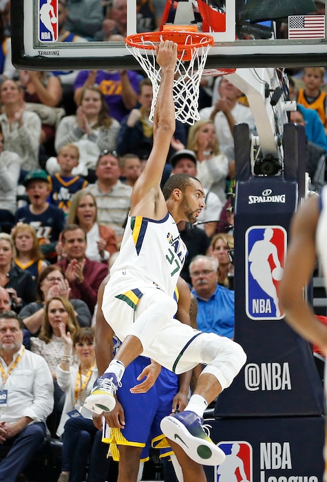 Utah Jazz center Rudy Gobert (27) hangs off the hoop after scoring against the Golden State Warriors in the first half during an NBA basketball game Friday, Oct. 19, 2018, in Salt Lake City. (AP Photo/Rick Bowmer)