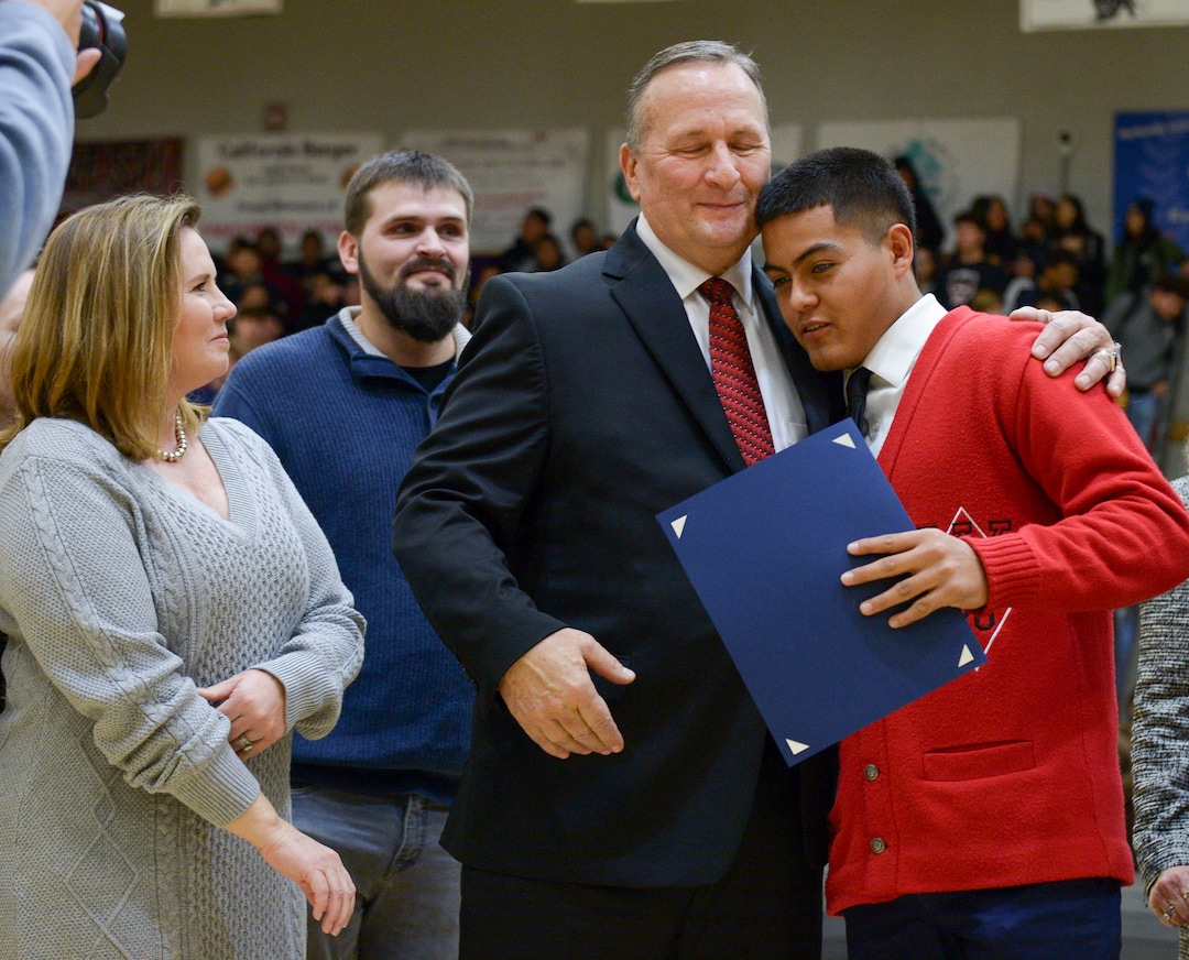 (Leah Hogsten  |  The Salt Lake Tribune) l-r Joey Carlson smiles as her husband, Assistant Attorney General David Carlson hugs West High School student, Felix Ortiz, as Ortiz is recognized during an assembly at the school, Jan. 17, 2020. On February 19, 2019, Ortiz and fellow student Grant Dunkley assisted Carlson out of his overturned car on the 600 North bridge in Salt Lake City where Ortiz performed life-saving CPR until first responders arrived on the scene.