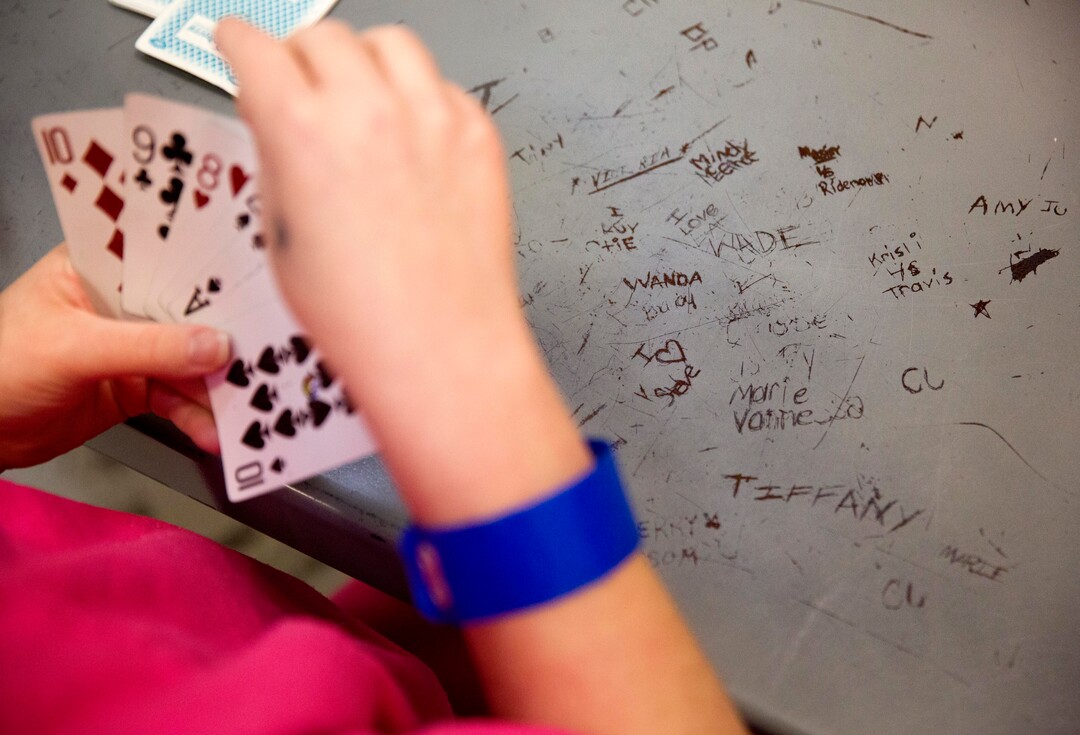Names are etched in a metal table as inmates play cards in the Campbell County Jail in Jacksboro, Tenn., Thursday, March 15, 2018. Inmates are confined to dormitory-like cells 23 hours a day, where they watch TV, play endless games of cards or pace in silent frustration, counting the days until their release. (AP Photo/David Goldman)