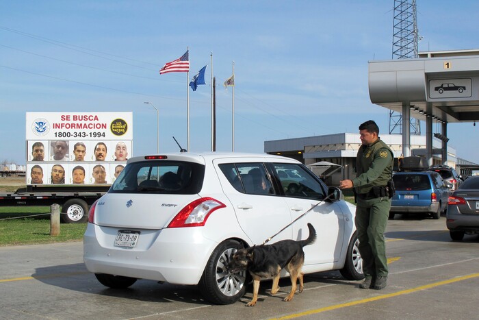 A Border Patrol agent uses a dog to inspect a car waiting to pass through the Laredo North vehicle checkpoint in Laredo, Texas, on Friday, February 2, 2018. The dogs are trained to catch drugs and people who try to enter the U.S. illegally in trunks and vehicle compartments. (AP Photo/Nomaan Merchant)