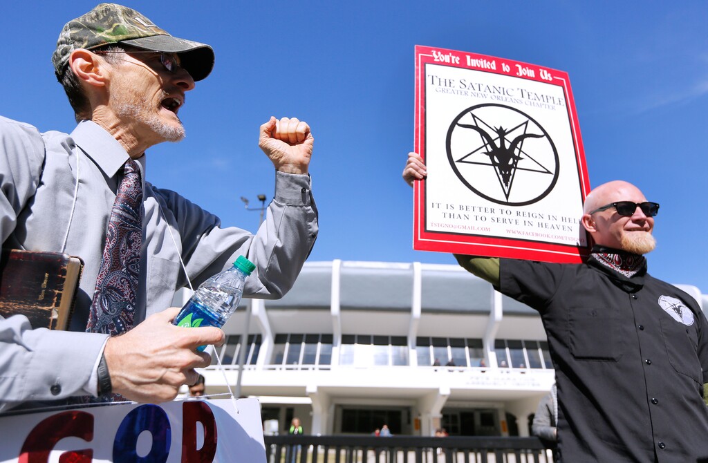 Tom Brewer Denham, left, preaches to Chris Bridges, holding a sign for The Satanic Temple, during a protest outside of an all-day prayer rally headlined by Gov. Bobby Jindal, Saturday, Jan. 24, 2015, in Baton Rouge, La. Jindal continued to court Christian conservatives for a possible presidential campaign with a headlining appearance at an all-day prayer rally hosted by the American Family Association. (AP Photo/Jonathan Bachman)