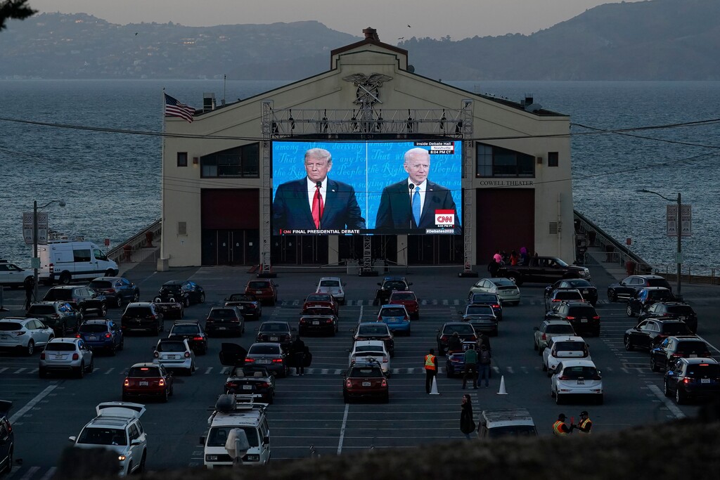 (Jeff Chiu | AP filephoto) People watch from their vehicles as President Donald Trump, on left of video screen, and Democratic presidential candidate former Vice President Joe Biden speak during a presidential debate watch party at Fort Mason Center in San Francisco, Thursday, Oct. 22, 2020. The debate party was organized by Manny's, a San Francisco community meeting and learning place.