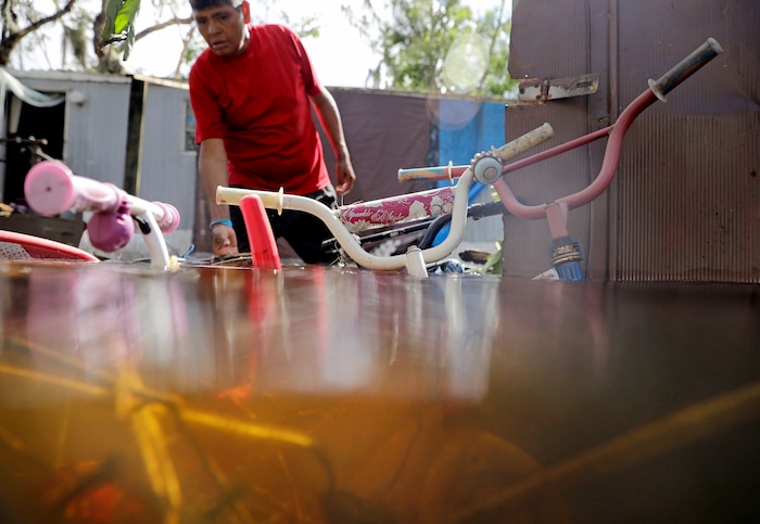 Children's bicycles are flooded outside a home as Ezequiel Cruz retrieves belongings in the aftermath of Hurricane Irma in Bonita Springs, Fla., Tuesday, Sept. 12, 2017. (AP Photo/David Goldman)