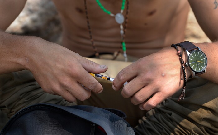 (Scott Sommerdorf | The Salt Lake Tribune) "Jonathan" holds the syringe with a dose of black tar heroin as he prepares to inject himself on the median near the needle exchange tent on 500 West & 300 South, Thursday, August 3, 2017.