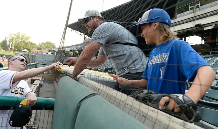 (Francisco Kjolseth  |  The Salt Lake Tribune)  Timmy (Victor DiMattia) one of the stars of the Utah-filmed "The Sandlot" hands over a signed baseball for young fan Rydge Butler, 11, alongside his dad Brett as the Salt Lake Bees celebrate the 25th anniversary of the film with members of the original cast at the Smith's Ballpark on Friday, Aug. 10, 2018.