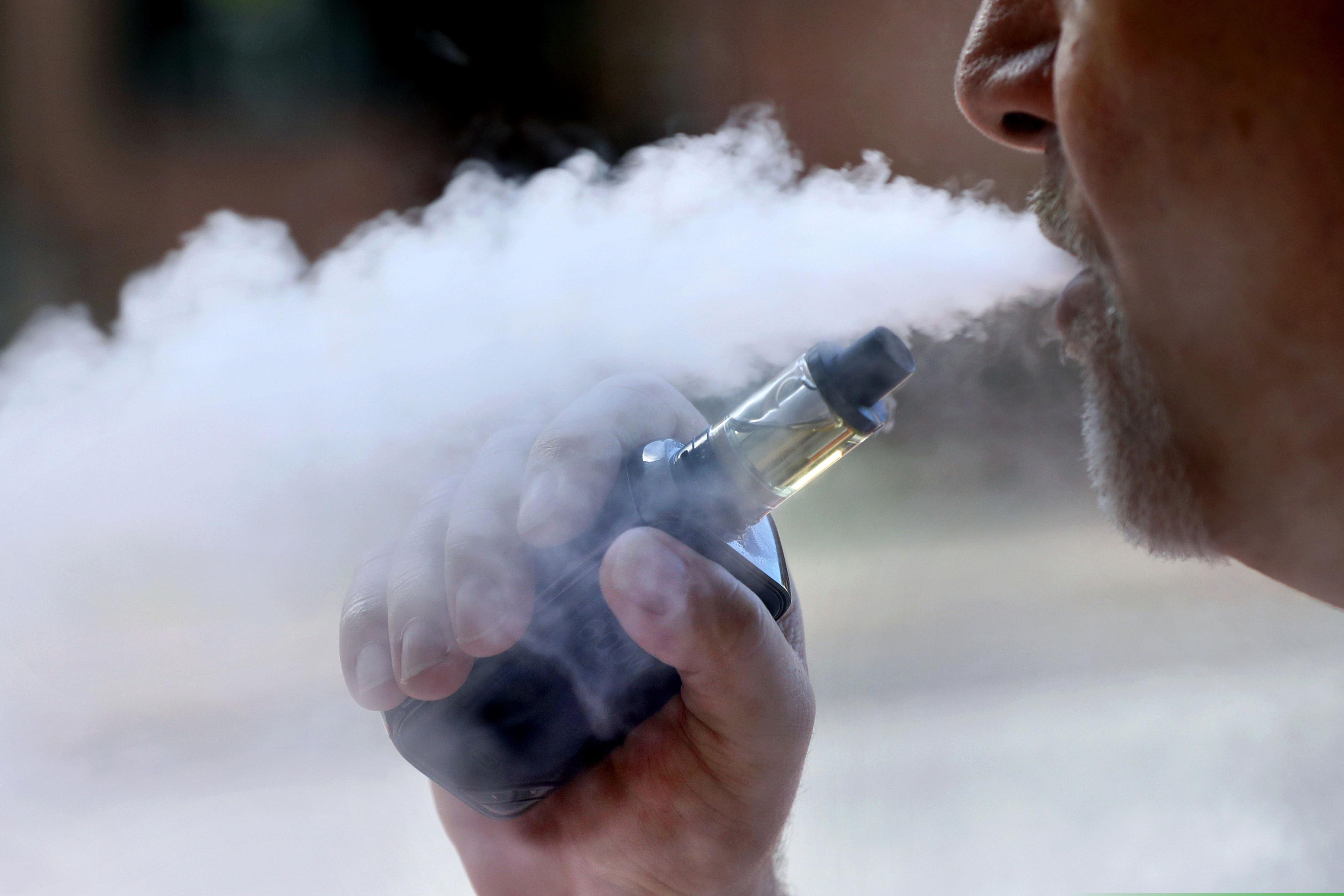 (Robert F. Bukaty | AP file photo) A man exhales while smoking an e-cigarette in Portland, Maine. A new Nevada law will expand the state’s clean-air law that already restricts smoking to also prohibit use of vaping products and electronic cigarettes in most public places and indoor places of employment.