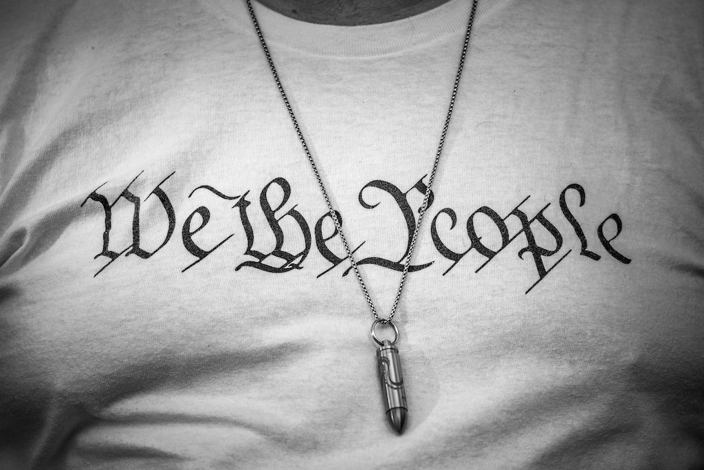 (Damon Winter | The New York Times) 

A person wears a bullet necklace over a "We the People" shirt in Miami, Jan. 6, 2022. "You cannot defend the ideal of “E pluribus unum” by deleting pluribus," writes New York Times columnist Bret Stephens.
