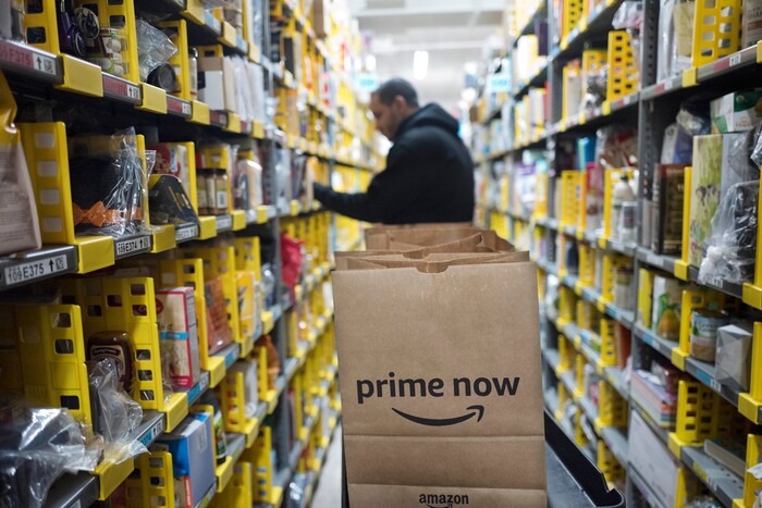 In this Wednesday, Dec. 20, 2017, photo, a clerk reaches to a shelf to pick an item for a customer order at the Amazon Prime warehouse, in New York. (AP Photo/Mark Lennihan)