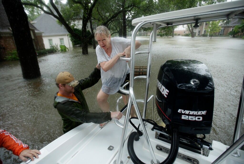 Beverly Bugler is helped onto a rescue boat as volunteers help evacuate a neighborhood inundated by floodwaters from Tropical Storm Harvey on Monday, Aug. 28, 2017, in Houston, Texas. (AP Photo/Charlie Riedel)