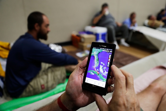(AP Photo/David Goldman) Tim Grollimund looks at the projected path of Hurricane Irma on his phone while staying in a shelter in Miami after evacuating his home in Key Largo along the Florida Keys, Saturday, Sept. 9, 2017.