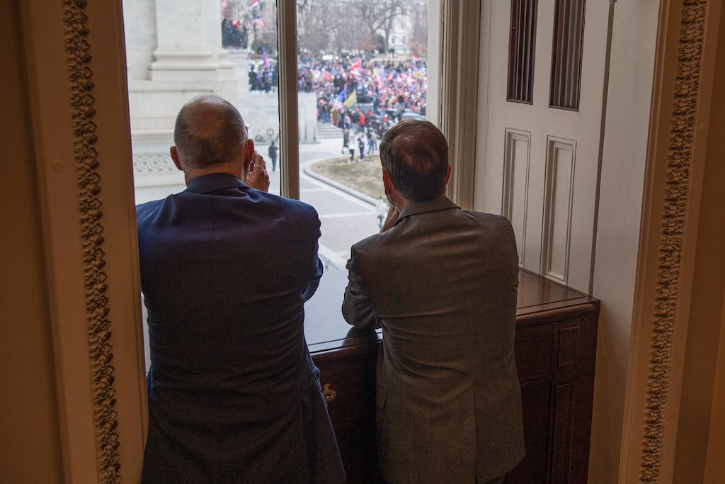 (Tom Williams | CQ Roll Call via AP) Reps. Tom O'Halleran, D-Ariz., left, and Chris Stewart, R-Utah, view rioters who broke into the Capitol during a joint session of Congress to certify the Electoral College votes of 2020 presidential election on Wednesday, Jan. 6, 2021.