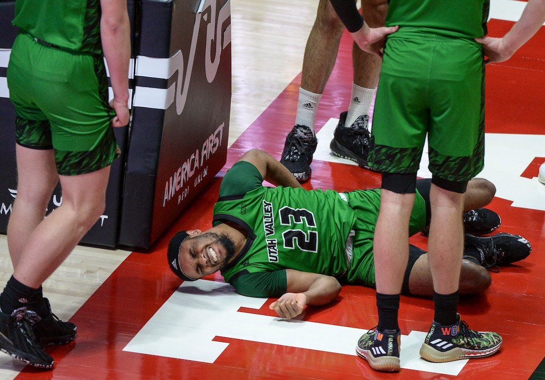 (Leah Hogsten  |  The Salt Lake Tribune) Utah Valley Wolverines guard Jordan Brinson (23) grimaces on the deck after flying over the back of Utah Utes guard Rylan Jones (15) as the Utes host Utah Valley University on Tuesday, Dec. 15, 2020 at the Jon M. Huntsman Center. The Utes won 75-67. Brinson left the game.