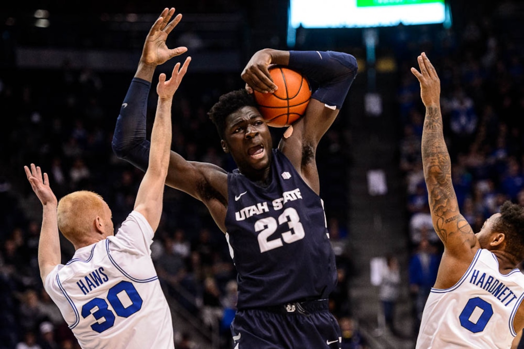 (Trent Nelson | The Salt Lake Tribune)  Utah State Aggies center Neemias Queta (23) pulls down a rebound with Brigham Young Cougars guard TJ Haws (30) at left as BYU hosts Utah State, NCAA basketball in Provo on Wednesday Dec. 5, 2018.