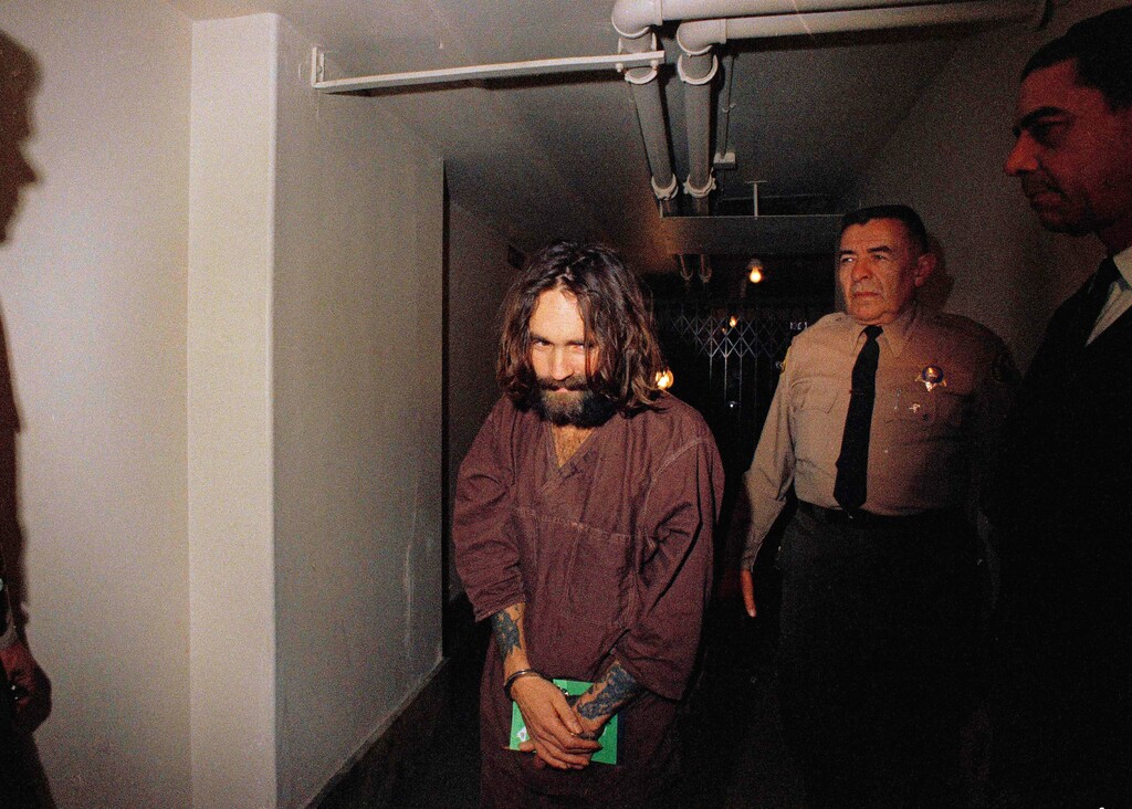 (The Associated Press) In this 1969 file photo, Charles Manson is escorted to court in Los Angeles during an arraignment phase. Authorities say Manson, cult leader and mastermind behind 1969 deaths of actress Sharon Tate and several others, died on Sunday, Nov. 19, 2017. He was 83.