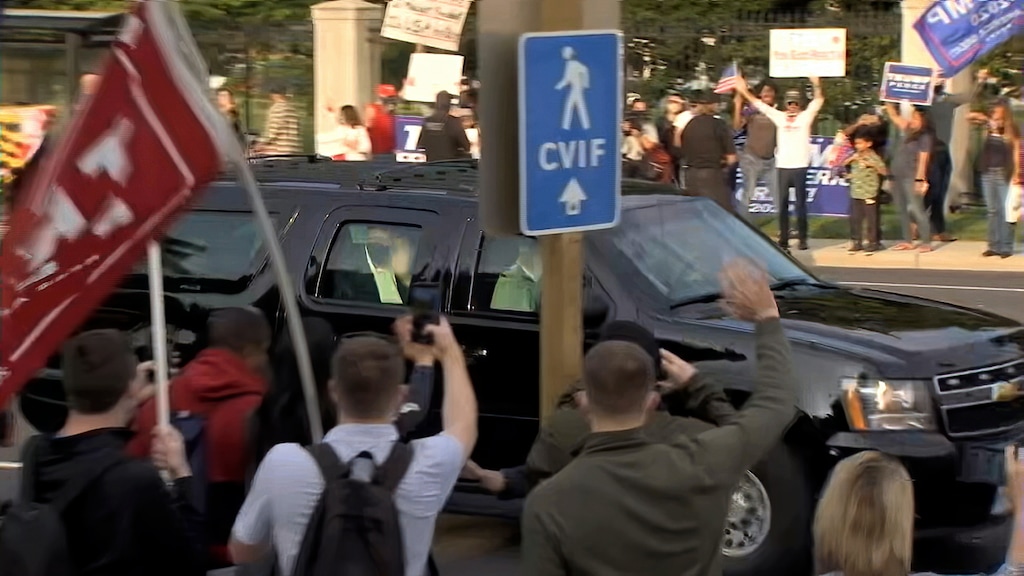 (Carlos Vargas | AP) In this image from video, President Donald Trump waves as he drives past supporters gathered outside Walter Reed National Military Medical Center in Bethesda, Md., Sunday, Oct. 4, 2020. Trump was admitted to the hospital after contracting COVID-19.