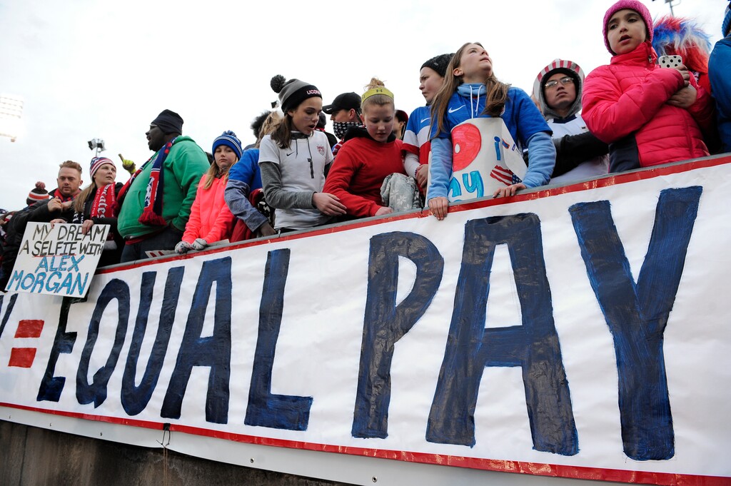 FILE - In this April 6, 2016, file photo, fans stand behind a large sign for equal pay for the women's soccer team during an international friendly soccer match between the United States and Colombia at Pratt & Whitney Stadium at Rentschler Field in East Hartford, Conn. The World Economic Forum's annual Global Gender Gap Report released on Oct. 25, 2016, found that the global gender pay gap will not be closed for another 170 years if current trends continue. (AP Photo/Jessica Hill, File)