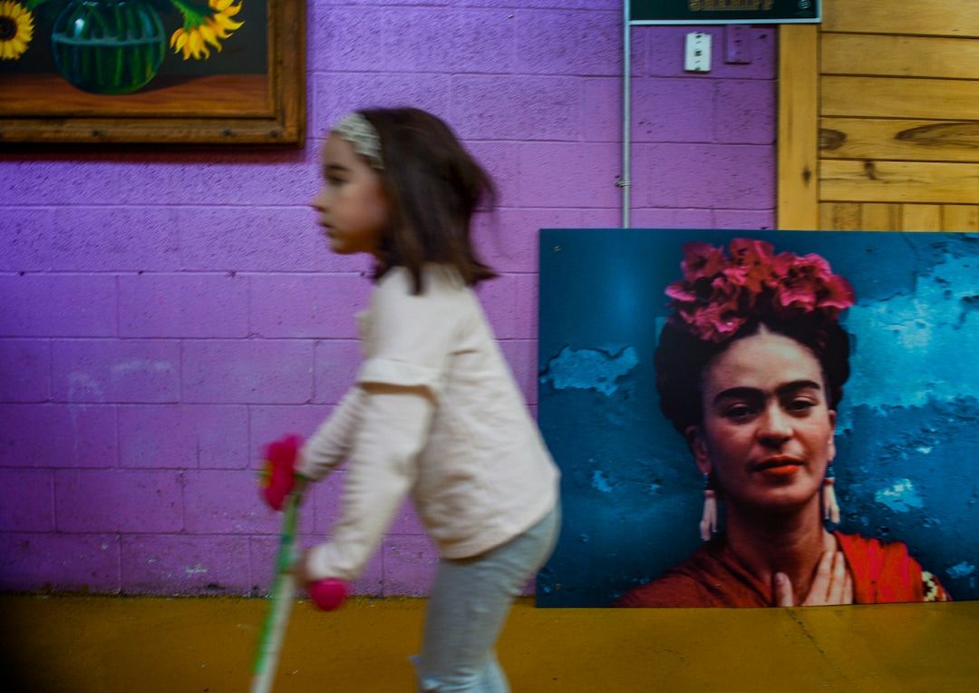 (Leah Hogsten  |  The Salt Lake Tribune)  Ella Fierro, 5, rides her scooter past a large sign of Mexican artist Frida Kahlo. Her father, Jorge Fierro recently changed the name and menu of his restaurant, Frida Bistro, to better reflect the Rico brand that he started more than 20 years ago.