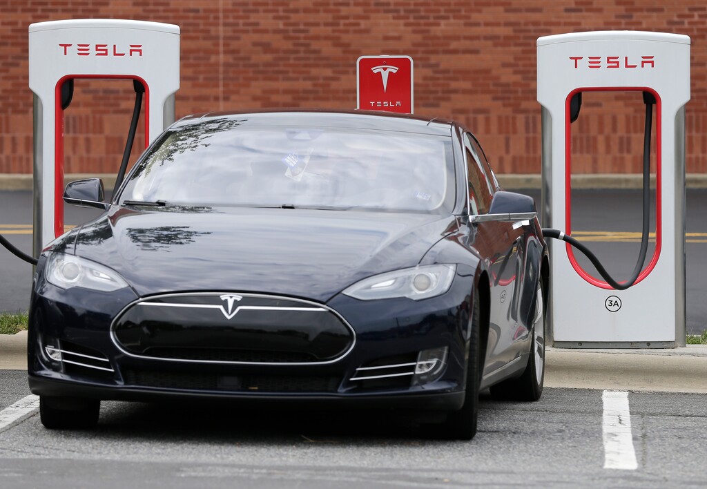 FILE - In this Saturday, June 24, 2017, file photo, a Tesla car recharges at a charging station at Cochran Commons shopping center in Charlotte, N.C. On Monday, Sept. 11, 2017, Tesla Inc. announced that more charging stations are on the way. The stations will be installed at places such as supermarkets and shopping centers, and in cities like Chicago and Boston. (AP Photo/Chuck Burton, File)