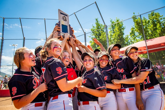 (Isaac Hale | Special to The Tribune) Spanish Fork players celebrate around the championship trophy after the Spanish Fork Lady Dons defeated the Mountain Ridge Sentinels in a best-of-three series to win the 5A state softball championship at the Spanish Fork Sports Park on Friday, May 28, 2021.