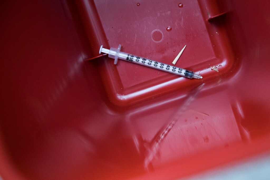 (Mary Altaffer | The Associated Press) In this Tuesday, July 3, 2018, photo, a used syringe removed from the bed of a sidewalk tree near VOCAL-NY headquarters in the Brooklyn borough of New York is seen in a disposal container. VOCAL-NY runs a needle exchange and harm reduction services, as well as overdose prevention and other services for people who use drugs.