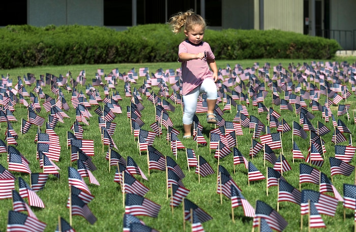 (Rick Egan | The Salt Lake Tribune) Lillian Edwards, 2 1/2, from Millcreek, walks through the 3000 flags in front of Skyline High School in memory of those who lost their lives 17 years ago. Tuesday, Sept. 11, 2018.