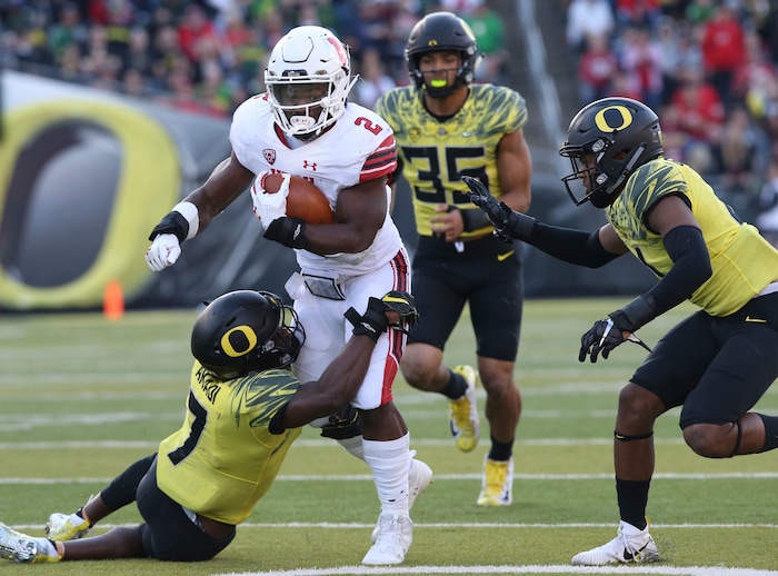 Oregon's Oregon cornerback Ugochukwu Amadi, left, works to pull down Utah running back Zach Moss with Oregon linebacker Troy Dye and cornerback Thomas Graham Jr. in pursuit during the third quarter of their NCAA college football game Saturday, Oct. 28, 2017, in Eugene, Ore. (AP Photo/Chris Pietsch)