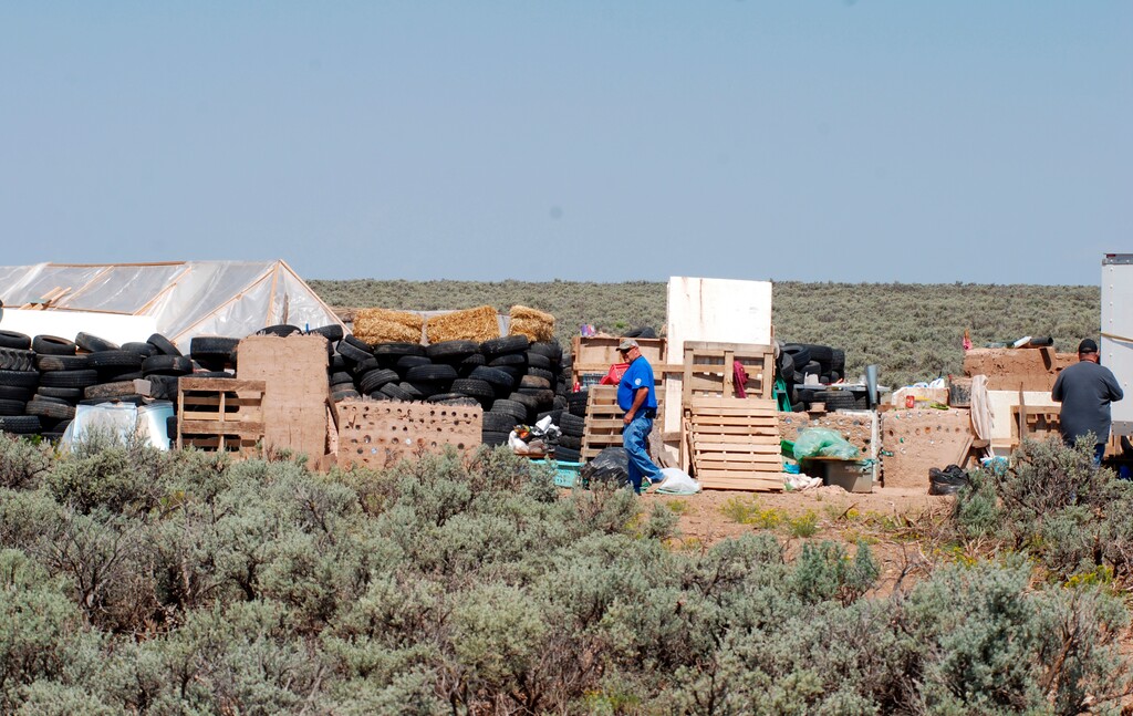 (AP Photo | Morgan Lee) Taos County Solid Waste Department Director Edward Martinez, center, surveys property conditions at a disheveled living compound at Amalia, N.M., on Tuesday, Aug. 7, 2018. A New Mexico sheriff said searchers have found the remains of a boy at the makeshift compound that was raided in search of a missing Georgia child.