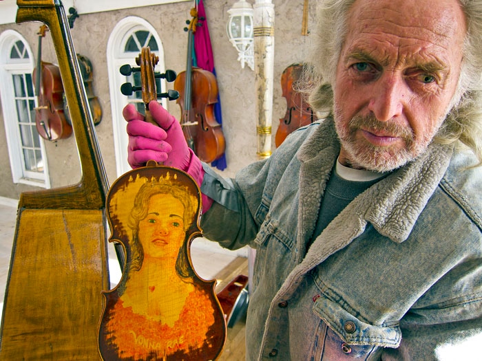 (Ed Kosmicki) Salt Lake City artist Ralphael Plescia, holding a portrait painted on a violin in a November 2012 photo. Plescia died Aug. 14, 2022, at age 84.
