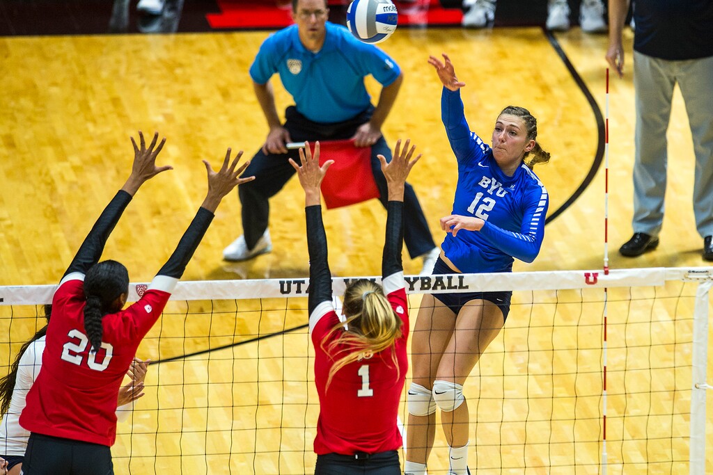 (Chris Detrick  |  The Salt Lake Tribune)  Brigham Young's Veronica Jones-Perry (12) hits past Utah's Dani Barton (1) and Utah's Tawnee Luafalemana (20) during the volleyball match at the Jon M. Huntsman Center Thursday, September 14, 2017. 
