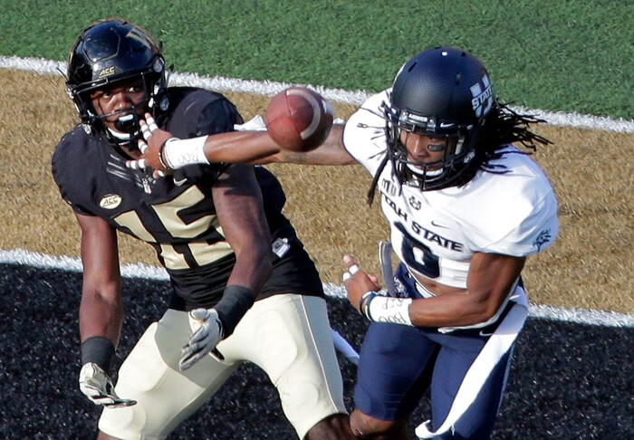 Wake Forest's Cortez Lewis (15) tries to catch a pass as Utah State's Wesley Bailey (8) defends in the second half of an NCAA college football game in Winston-Salem, N.C., Saturday, Sept. 16, 2017. Bailey was called for interference on the play. (AP Photo/Chuck Burton)