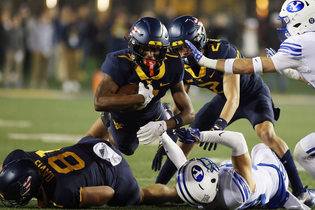 West Virginia's Traylon Ray, top, jumps over players during the first half of an NCAA college football game against BYU on Saturday, Nov. 4, 2023, in Morgantown, W.Va. (AP Photo/Chris Jackson)