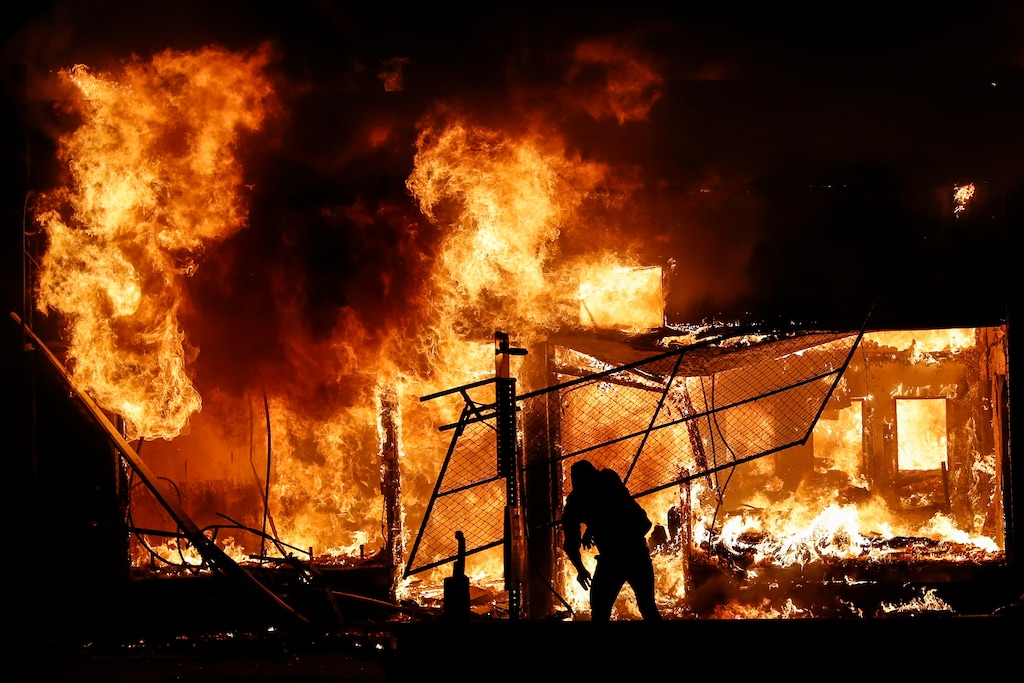 (John Minchillo | AP photo)

In this May 30 photo, a protester adds materials to a fire of a building that once housed a check cashing business, in St. Paul, Minn. The destruction caused by vandals and looters in cities across the country, who struck as demonstrators took to the streets in reaction to the killing of George Floyd in Minneapolis, has devastated small businesses already reeling from the coronavirus outbreak.