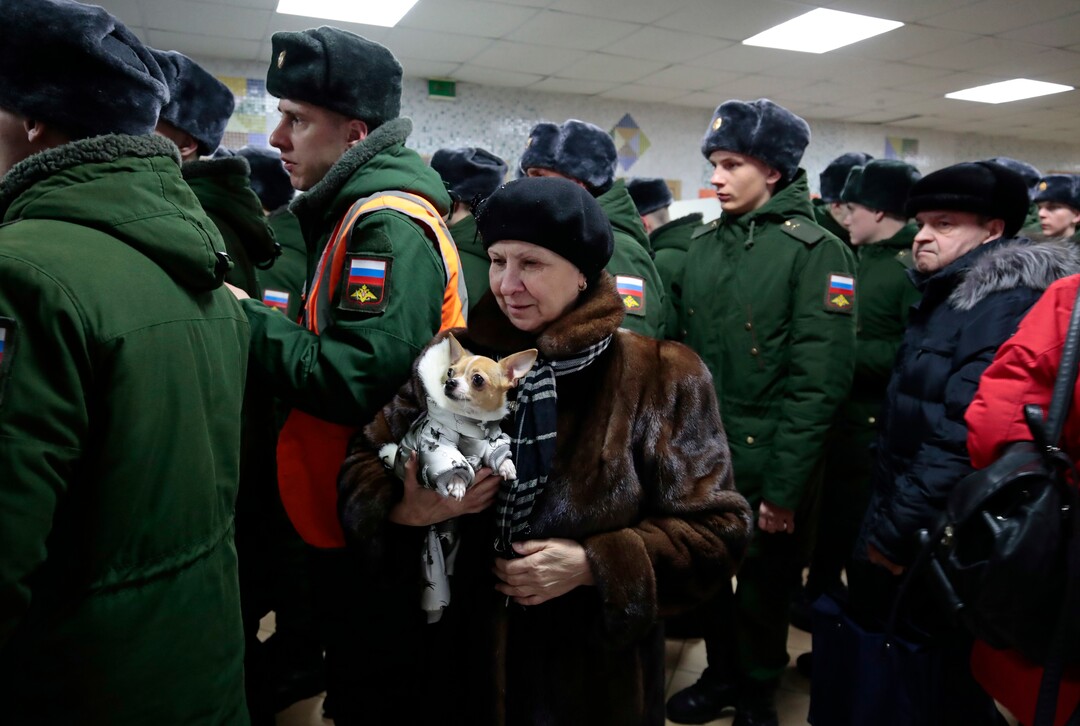 A woman with her dog lines up with Russian military personnel to vote in the presidential election in Moscow, Russia, Sunday, March 18, 2018. Russians are voting in a presidential election in which Vladimir Putin is seeking a fourth term in the Kremlin. (AP Photo/Denis Tyrin)