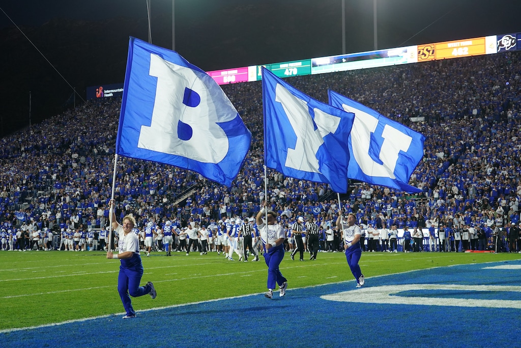 (George Frey | Special to The Tribune) BYU Cougars cheerleaders run BYU flags on the field after touchdown during a game against Notre Dame Fighting Irish at LaVell Edwards Stadium on October 17, 2026.