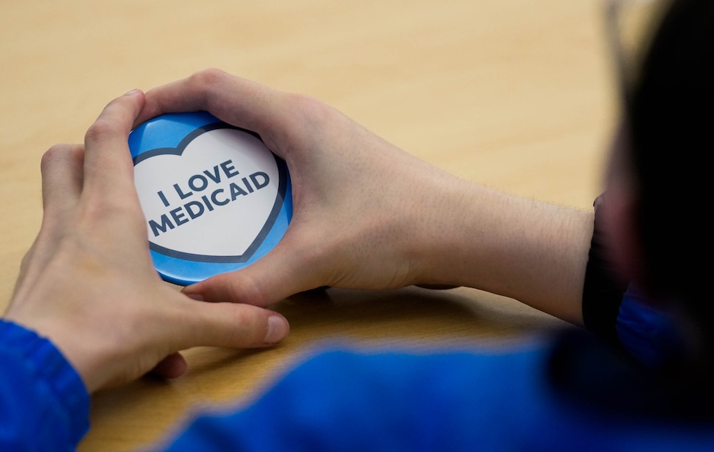 (Francisco Kjolseth | The Salt Lake Tribune) Brian James, 27, a cancer survivor with numerous disabilities, holds a “I Love Medicaid,” button as he joins his parents for a public hearing by the Utah Department of Health and Human Services on a proposal to impose work requirements on Medicaid recipients on Wednesday, May 14, 2025.