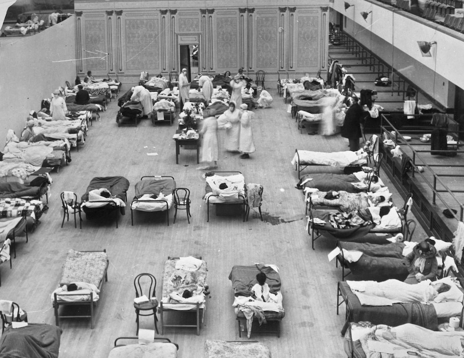 (Edward A. "Doc" Rogers/Library of Congress via AP) In this 1918 photo made available by the Library of Congress, volunteer nurses from the American Red Cross tend to influenza patients in the Oakland Municipal Auditorium, used as a temporary hospital.