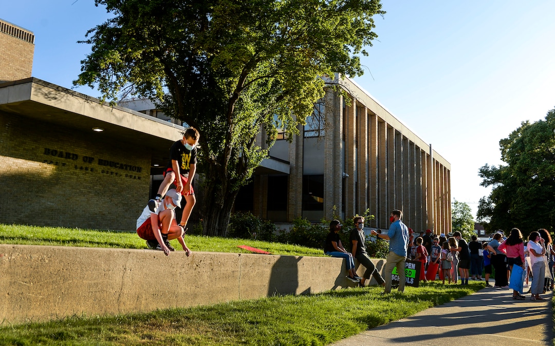 (Leah Hogsten  |  The Salt Lake Tribune) Best friends Will Hatch, top, and Welch McCormick play leap frog as the rally winds down on Wednesday evening. Parents and students within the Salt Lake City School District rally for K-12 students to return in-person to school this fall, July 15, 2020.