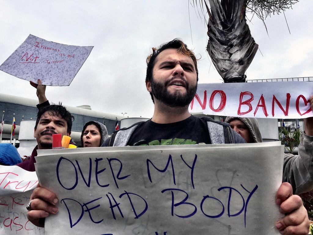 Franklyn Saumell protests against President Trump's refugee ban at Miami International Airport on Sunday, Jan. 29, 2017. President Donald Trump’s immigration order sowed more confusion and outrage across the country Sunday, with travelers detained at airports, panicked families searching for relatives and protesters registering their opposition to the sweeping measure. (C.M. Guerrero/El Nuevo Herald via AP)