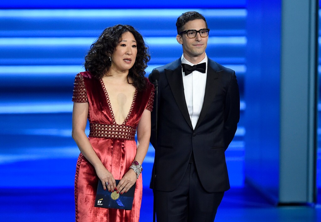 (Chris Pizzello | Invision | The Associated Press) In this Sept. 17, 2018 file photo, Sandra Oh, left, and Andy Samberg present an award at the 70th Primetime Emmy Awards in Los Angeles. Oh and Samberg will share host duties at next month’s Golden Globe ceremony.
