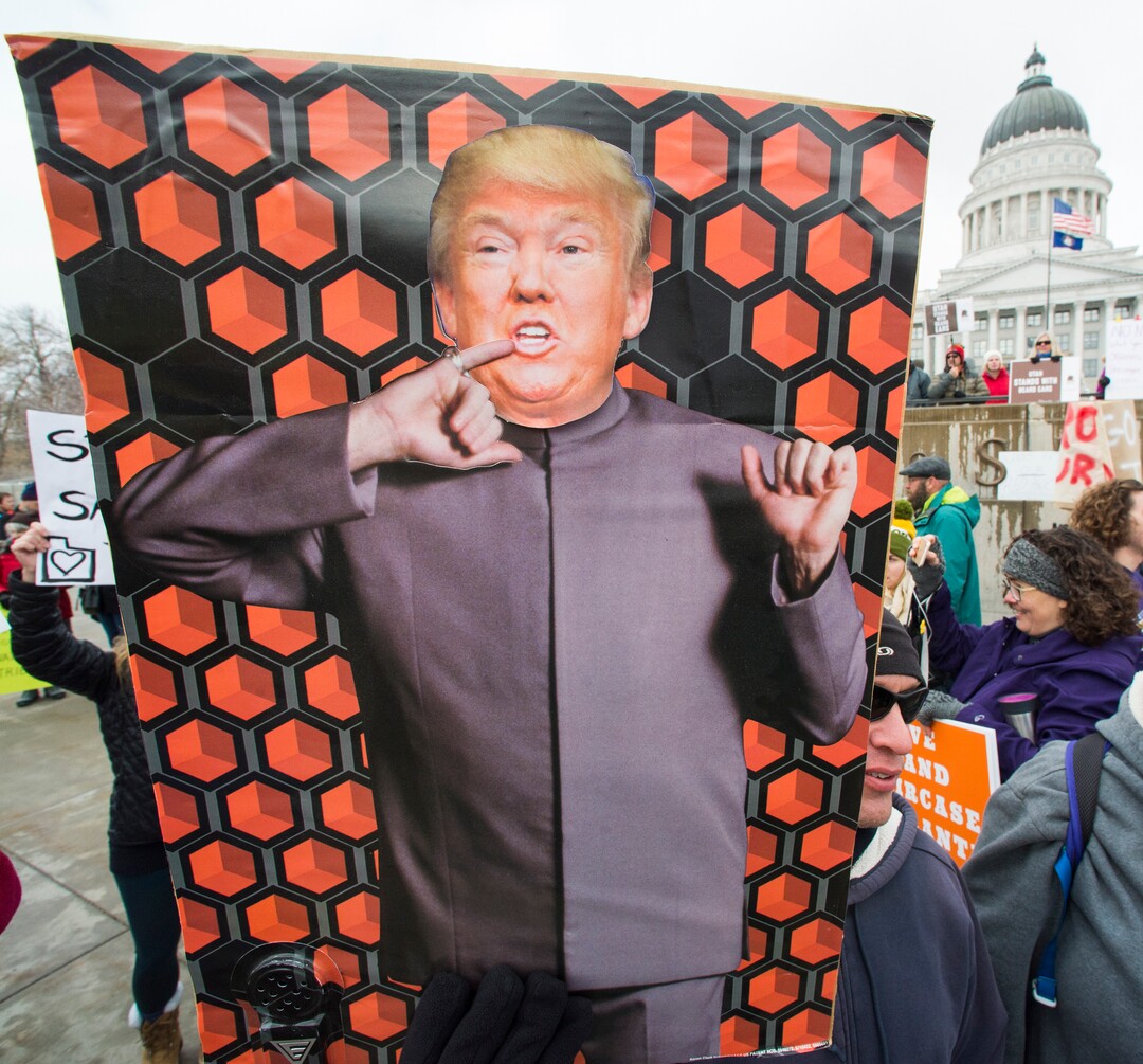 (Rick Egan  |  The Salt Lake Tribune)  Steve Oliver holds a sign while protesting President Trump's visit to Salt Lake City to shrink two national monuments, at the Utah State Capitol, Monday, December 4, 2017.