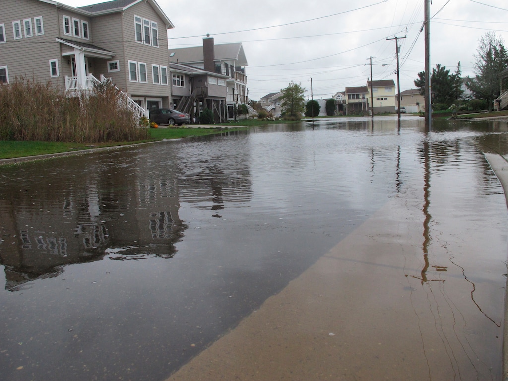 Flood waters cover the street, sidewalks and lawns of a neighborhood in Ocean City, N.J. on Oct. 30, 2020. The city is dealing with the costs of rising sea levels, both in monetary terms and in the disruption that recurring flooding brings. (AP Photo/Wayne Parry)
