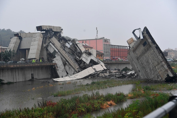 Rescuers work among the rubble of the collapsed Morandi highway bridge in Genoa, northern Italy, Tuesday, Aug. 14, 2018. A large section of the bridge collapsed over an industrial area in the Italian city of Genova during a sudden and violent storm, leaving vehicles crushed in rubble below. (Luca Zennaro/ANSA via AP)
