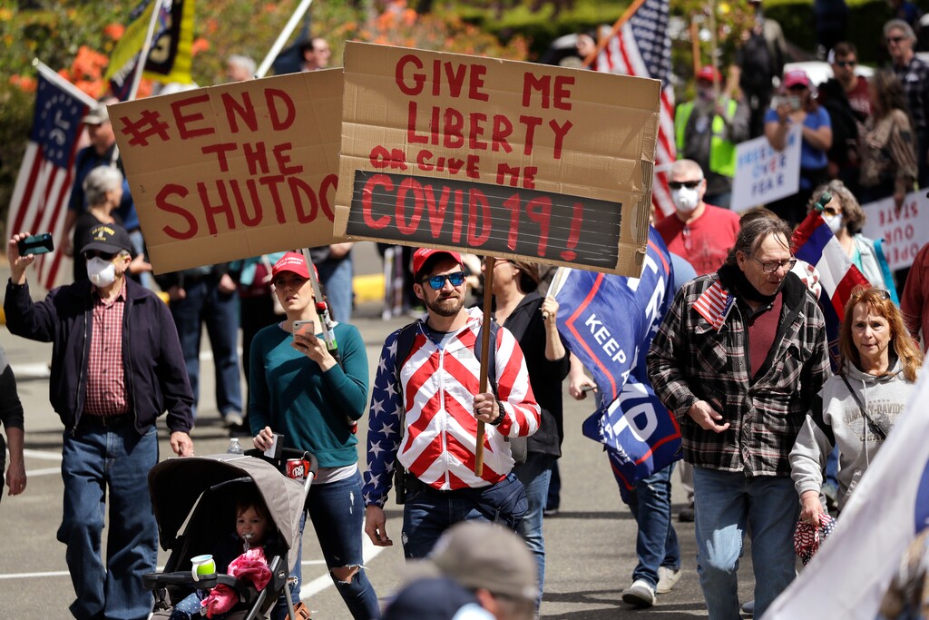 Demonstrators begin to gather at a protest opposing Washington state's stay-home order to slow the coronavirus outbreak Sunday, April 19, 2020, in Olympia, Wash. Washington Gov. Jay Inslee has blasted President Donald Trump's calls to "liberate" parts of the country from stay-at-home and other orders that are designed to combat the spread of the coronavirus. Inslee says that Trump is fomenting a potentially deadly "insubordination" among his followers before the pandemic is contained. (AP Photo/Elaine Thompson)
