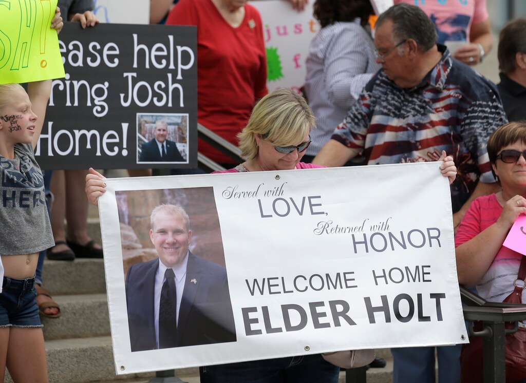 FILE - In this July 30, 2016, file photo, a woman holds a photograph of Josh Holt, an American jailed in Venezuela, during a rally at the Utah State Capitol, in Salt Lake City. A judge in Venezuela is dashing the hopes of the Utah man of being united with his family for Christmas after deciding on Dec. 12, 2017 to send him to trial on weapons charges. (AP Photo/Rick Bowmer, File)