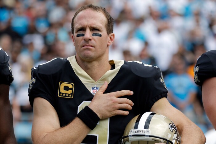 New Orleans Saints quarterback Drew Brees (9) stands with his hand over his heart during the national anthem before an NFL football game against the Carolina Panthers in Charlotte, N.C., Sunday, Sept. 24, 2017. Several Saints players sat on the bench during the anthem. (AP Photo/Bob Leverone)