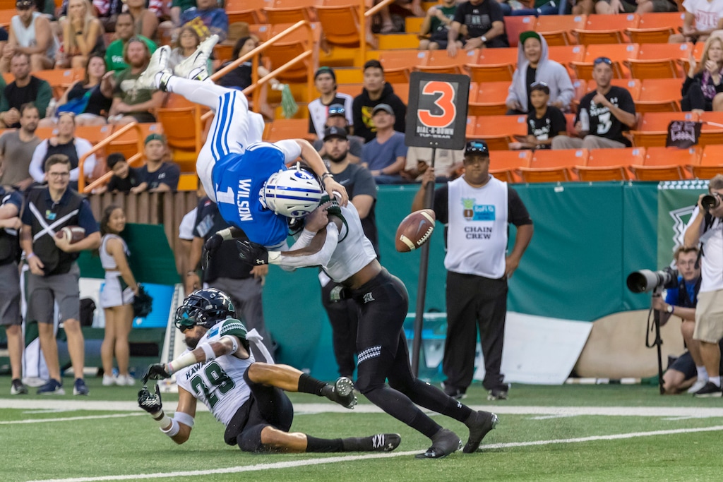 (Eugene Tanner | AP) BYU quarterback Zach Wilson (1) loses the football on a hit by Hawaii defensive back Eugene Ford, right, as Wilson tried to leap into the end zone during the second half of the Hawaii Bowl NCAA college football game Tuesday, Dec. 24, 2019, in Honolulu. Hawaii recovered the football in the end zone for a touchback.