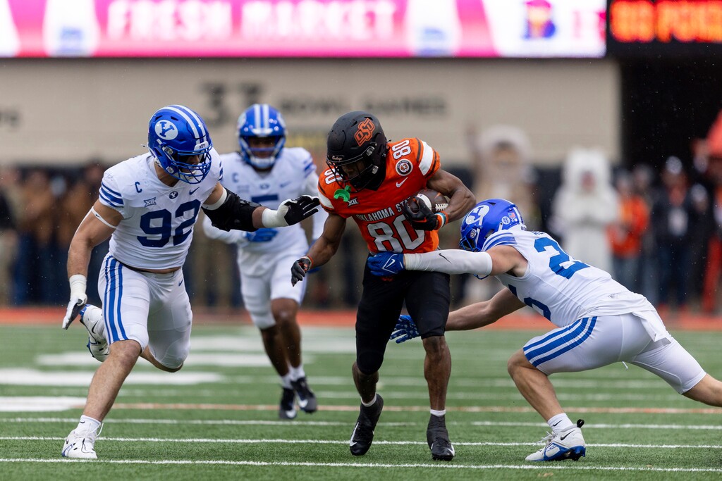 BYU safety Talan Alfrey (25) and defensive end Tyler Batty (92) tackle Oklahoma State wide receiver Brennan Presley (80) in the first half of an NCAA college football game Saturday, Nov. 25, 2023, in Stillwater, Okla. (AP Photo/Mitch Alcala)