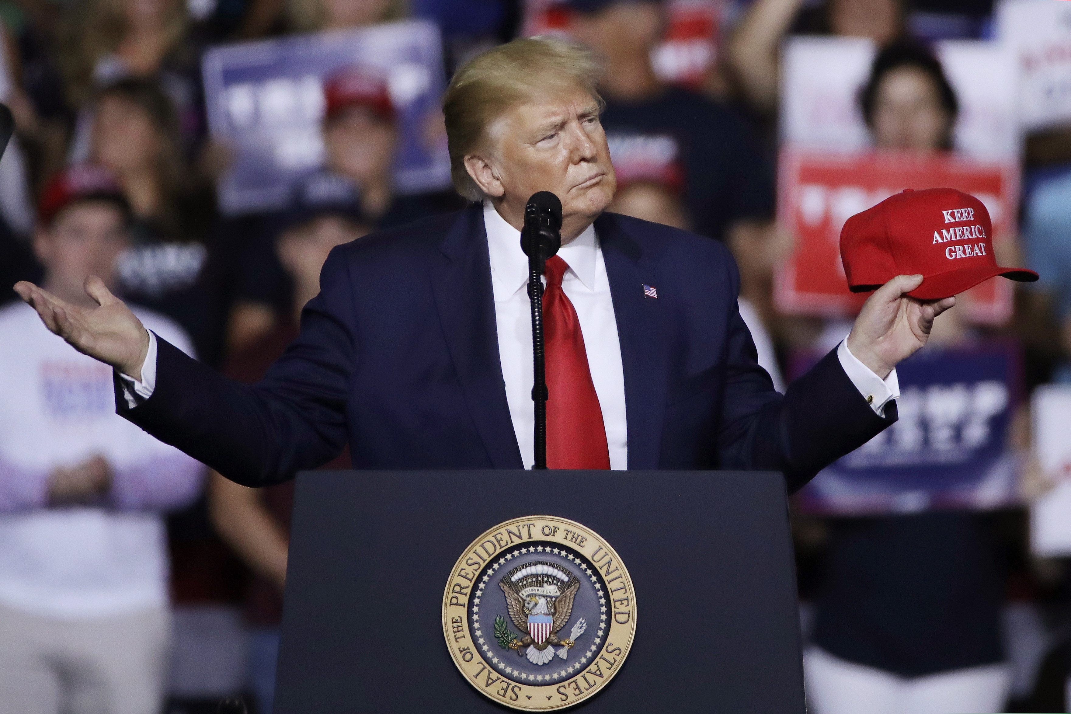 (Elise Amendola | AP file photo) President Donald Trump holds a "Keep America Great" hat as he speaks at a campaign rally on Thursday, Aug. 15, 2019, in Manchester, N.H.
